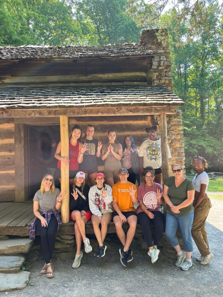 2023 Cohort stand in front of a cabin