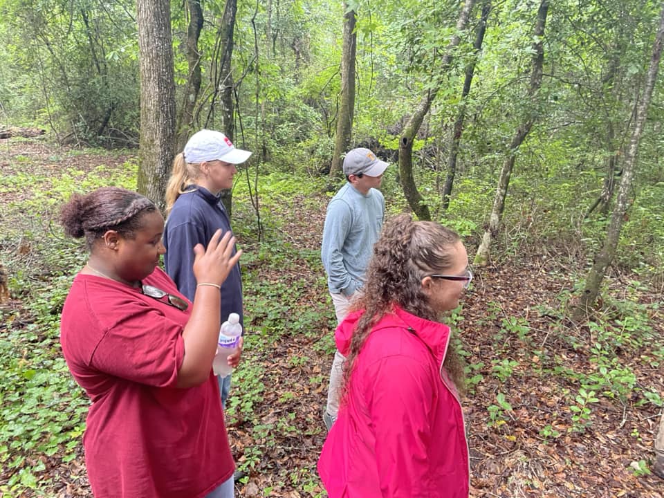 2023 Cohort standing in area surrounded by trees