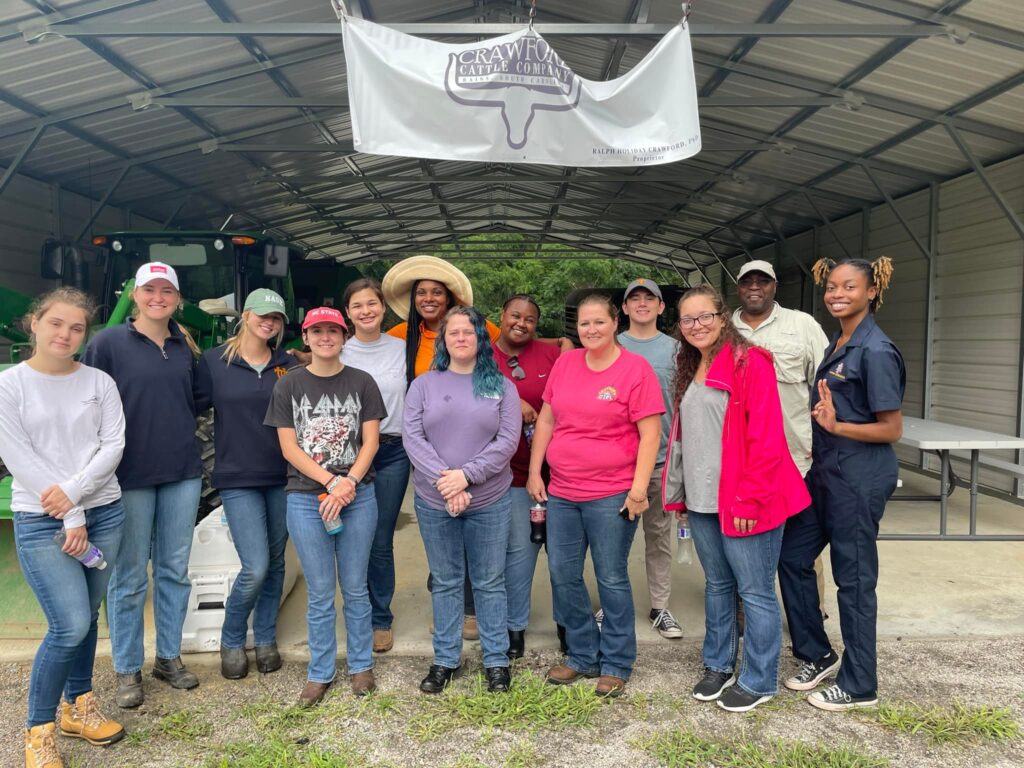 2023 Cohort standing in front of outdoor building with Crawford Cattle Company banner hanging above them