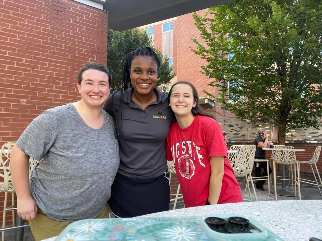 Three women smiling for camera at outdoor event