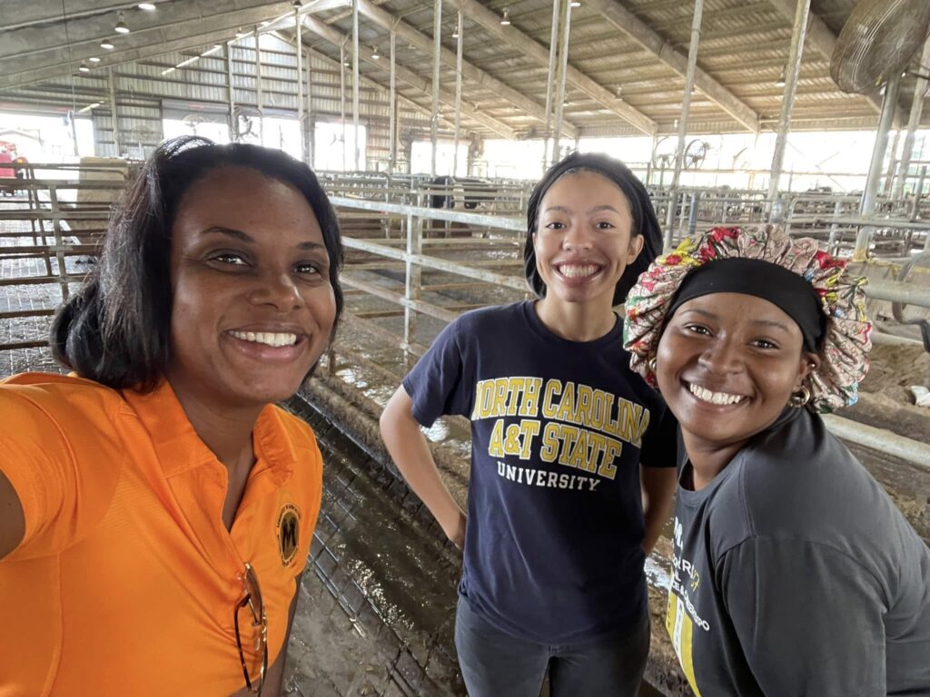 Three people smile for the camera at a dairy barn