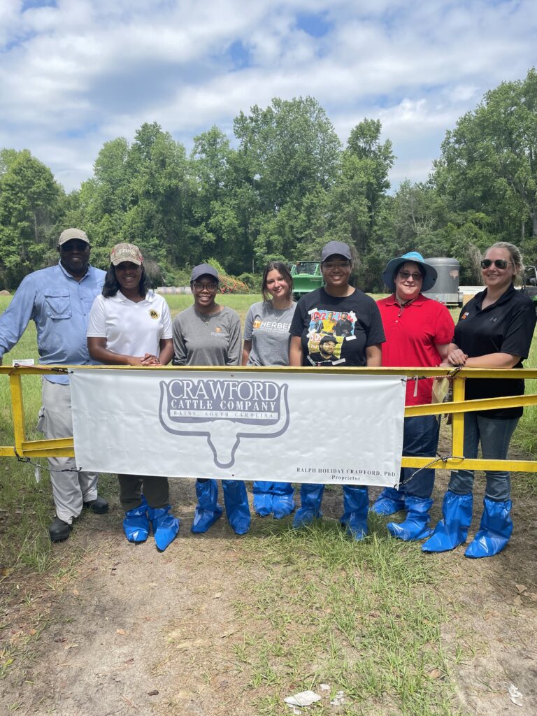 A group of people behind a gate with a sign that says Crawford Cattle Company