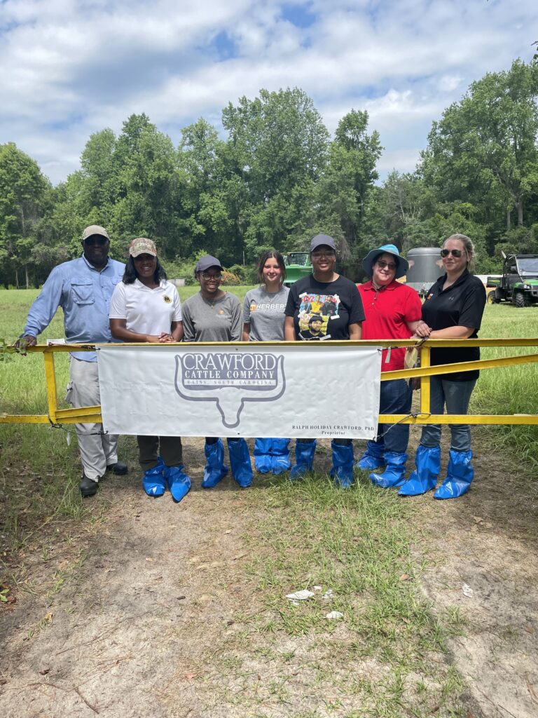 A group of people behind a gate with a sign that says Crawford Cattle Company