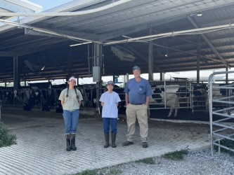 three people posing inside a dairy barn