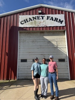 three students standing in front of a Chaney Farm barn