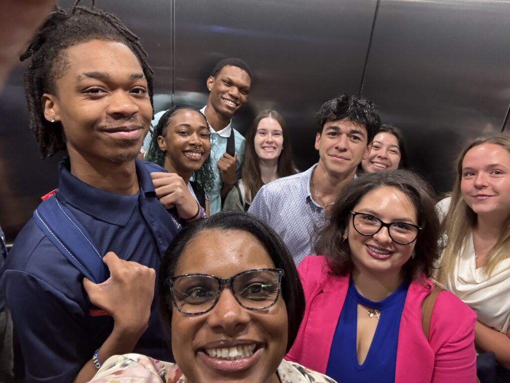 Group of people smiling for the camera while in an elevator