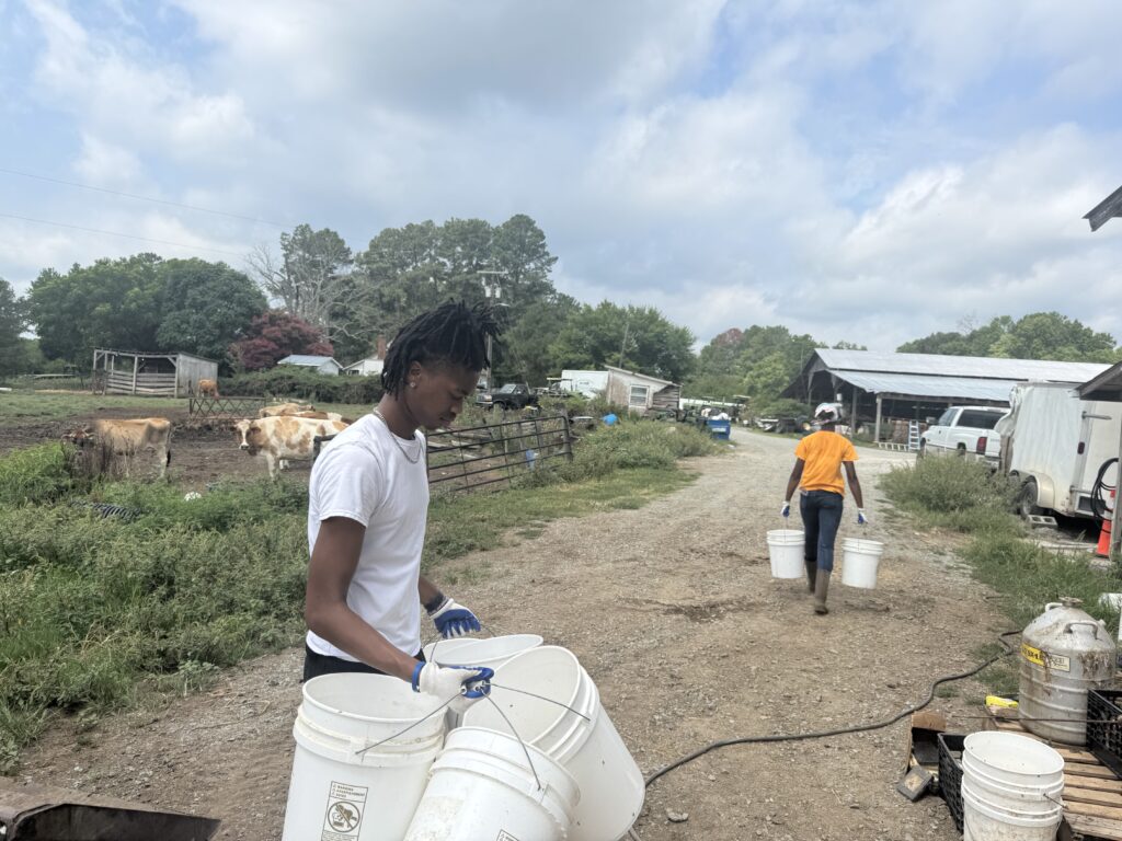 Two people carrying white 5-gallon buckets