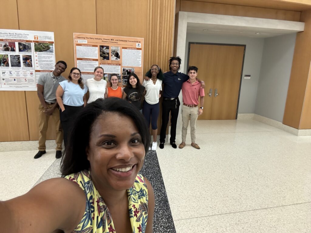 Group of students smiling in front of posters with Dr. Jean-Philippe in front of them
